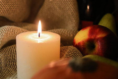 白蜡烛柔和的灯光和苹果,上面有水滴,背景是麻布.闭合.照片