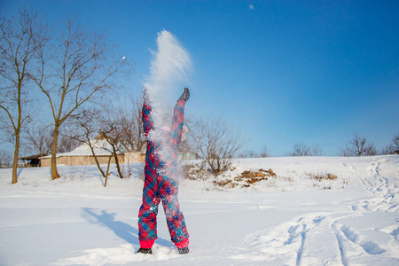 在一个阳光明媚的冬日里，快乐的女孩在扔雪。与雪的积极游戏。寒假。