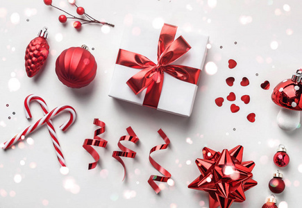 圣诞装饰，礼品盒与红丝带，火花，五彩纸屑，圣诞糖果和球在白色背景。圣诞快乐，新年快乐，阳光明媚。平放，俯视图
