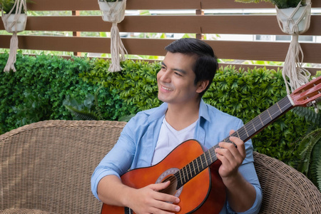 在花园的家里，男人一边弹吉他，一边微笑着唱着歌