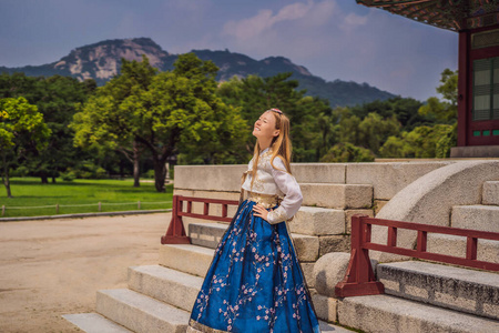 年轻的高加索女游客穿着韩服在庆冈宫。韩国旅游概念。韩国民族服装。游客娱乐尝试民族韩国语