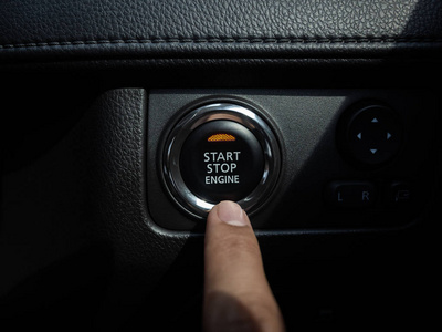 StartStop engine button with orange light on black car console 