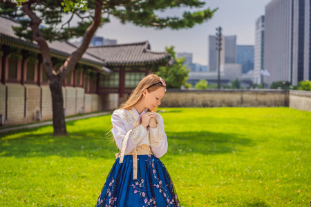 年轻的高加索女游客穿着韩服在庆冈宫。韩国旅游概念。韩国民族服装。游客娱乐尝试民族韩国语