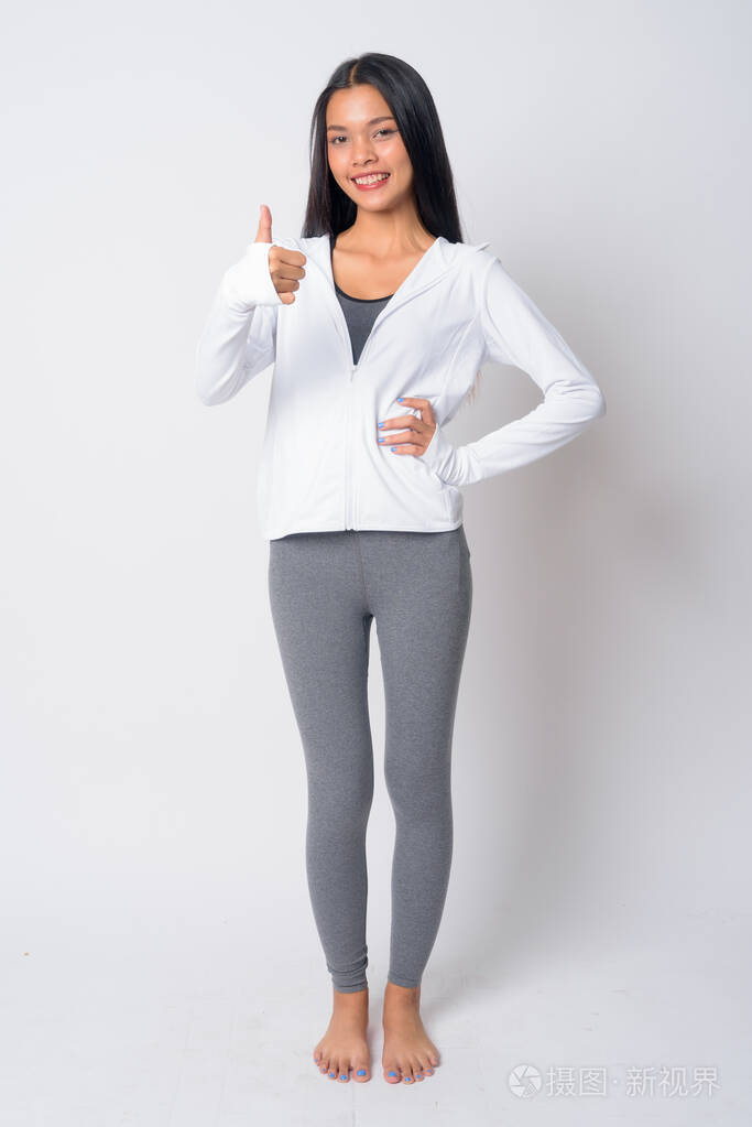 快乐的亚洲年轻女子竖起大拇指准备健身的全身照