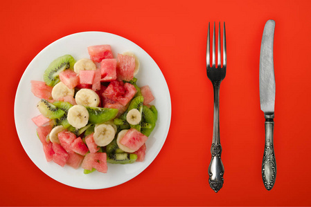 背景为白色盘子的新鲜水果沙拉。健康食品俯视图。