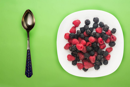 黑莓和覆盆子放在白色盘子里。黑莓和覆盆子背景俯视图。素食。