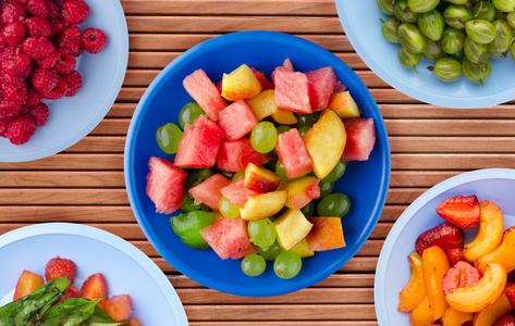 橙色木质背景的蓝色盘子上有水果。盘子顶部有水果健康视图吃东西。