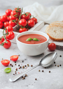White bowl plate of creamy tomato soup with spoon on light table