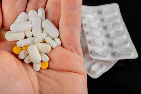 Medical tablets on a male hand. Medication on a dark table. 