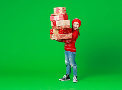 快乐有趣的小女孩戴着红色圣诞帽，绿色礼物