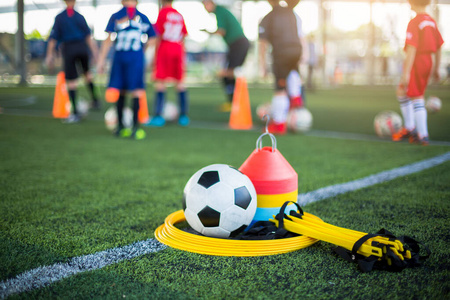 Ladder drills, soccer ball and marker cones on green artificial 