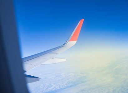 从飞机的窗户望去，在美丽的蓝天和阳光明媚的黎明中飞翔
