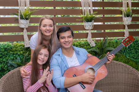 father play guitar or music with daughter and mother sitting on 