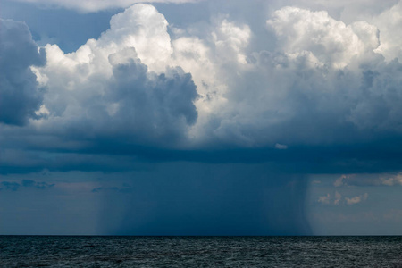 海上地平线上有雷雨。灰色的雷云。在远处，元素的大小是清晰可见的。