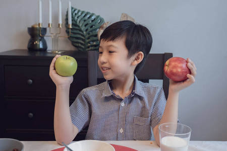 Asian boy smiling and holding apple red and green for eating in 