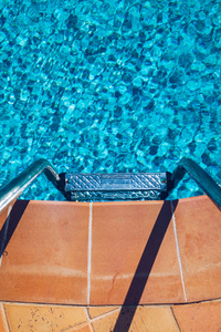 Swimming pool with stair. Grab bars ladder in the blue swimming 