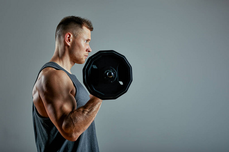 男子做背部锻炼,杠铃划船在工作室灰色背景.复制空间照片