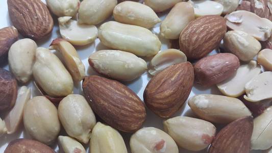 干烤花生和杏仁去壳.以水果为背景照片