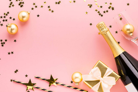 闪亮的纸吸管一瓶香槟酒礼物,淡粉色背景上有缎子蝴蝶结.