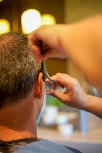 从顾客身后看，理发师用理发器或理发器剃头。