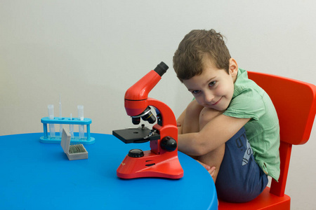 化学。科学。实验。教育。学习。聪明的男孩在用显微镜和试管工作。拿着试管的小孩。现代技术