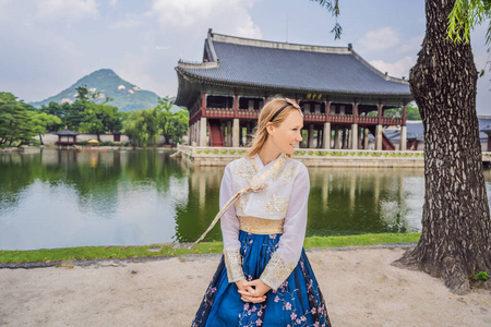 年轻的高加索女游客穿着韩服在朝鲜宫。韩国旅游概念。韩国民族服装。游客娱乐试穿韩国民族服装