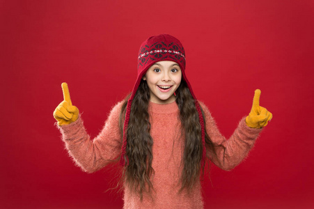 看这里。小女孩冬季时尚配饰。小孩戴着紫红色背景的帽子。享受可爱的冬装造型。呈现概念。冬装。小孩子戴针织帽子。保持温暖