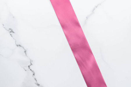 Pink silk ribbon and bow on marble background, girl baby shower 