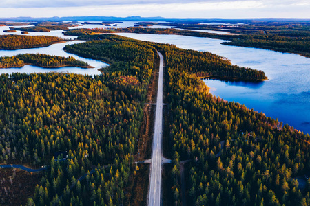 芬兰秋林蓝色湖泊公路鸟瞰图。