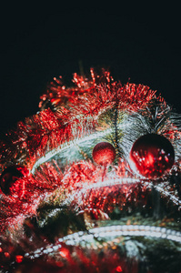 装饰圣诞树特写。红色的球和一个有灯笼照明的花环。新年装饰品宏观照片与博克。寒假灯饰