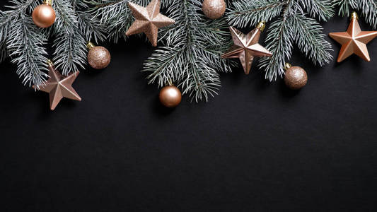圣诞横幅。圣诞树的树枝在黑色的背景上装饰着古铜的星星和球。平面布置，俯视图，复印空间。新年寒假圣诞节概念。