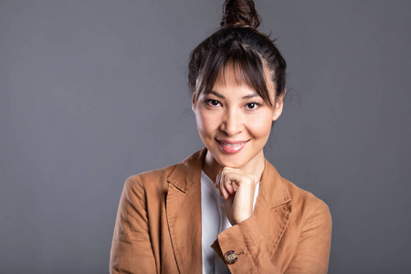 Headshot of happy Asian woman on gray background. 