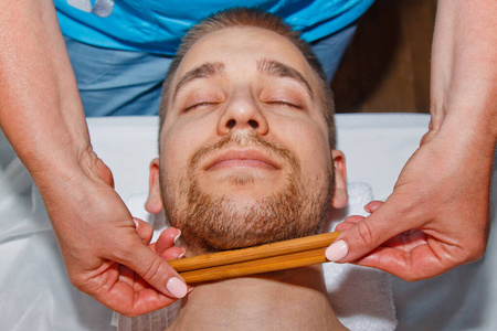 专业按摩师在温泉中心用特制的给男人做泰式面部按摩.