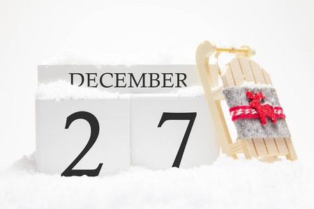 12月的木制日历，冬月的27日。冬天的象征是雪和雪橇。度假度假和冬季娱乐的概念。