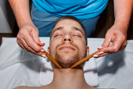 专业按摩师在温泉中心用特制的给男人做泰式面部按摩.