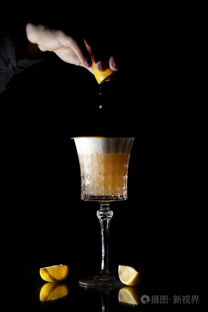 调酒师在黑色背景上调制经典的琥珀色鸡尾酒