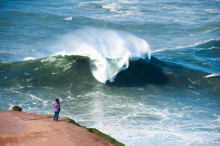 Tourist watching big waves in Nazare, Portugal. 