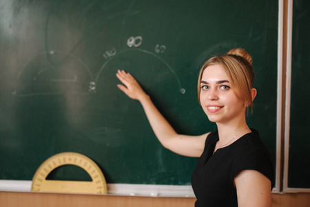 老师帮助黑板旁的女孩。青年女教师学习