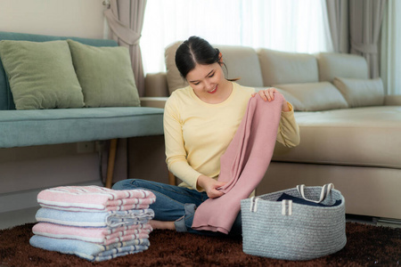 微笑的亚洲女人在家里拿着干净的叠好的衣服.漂亮照片