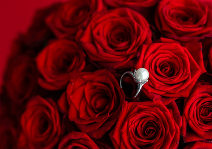 美丽的白金珍珠戒指和一束红玫瑰，奢华