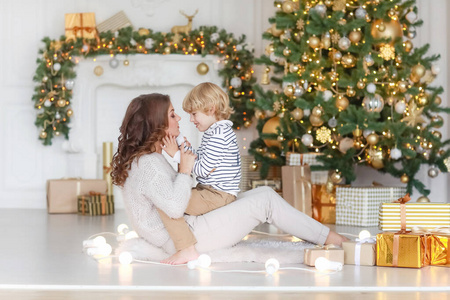 妈妈和儿子在家里的圣诞树下摆姿势。