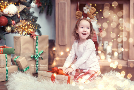 圣诞树旁的女孩闭着眼睛许愿。