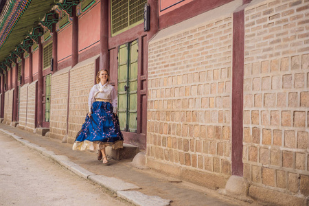 年轻的高加索女游客穿着韩服在朝鲜宫。韩国旅游概念。韩国民族服装。游客娱乐试穿韩国民族服装