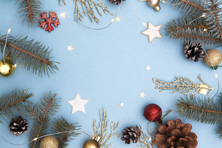 圣诞公寓。圣诞节和新年假期概念照片。冷杉树和金色的树枝，圆锥体，星星，花环和雪花在蓝色的背景上。复制文本空间