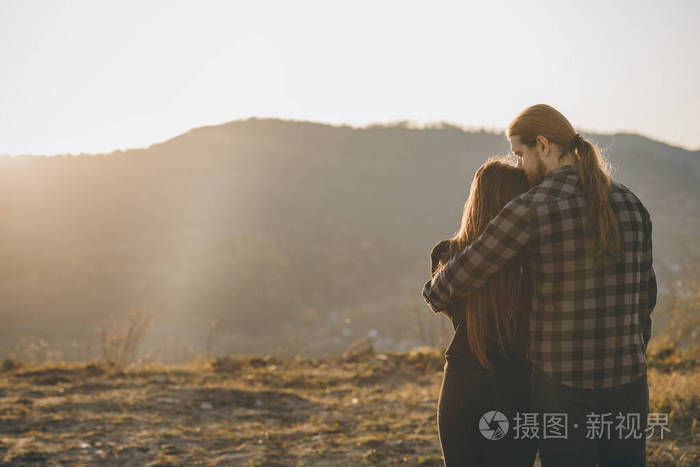 情侣们在山上的自然背景下手牵着手看着太阳升起喜欢黑影的人拥抱亲吻