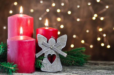 红色蜡烛和装饰天使圣诞和新年复古木桌和花环灯背景。
