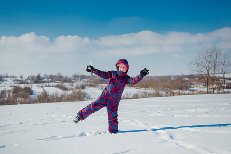 在一个阳光明媚的冬日里，欢快的女孩在雪地里跳跃。与雪的积极游戏。寒假。