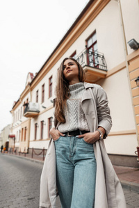 Elegant young woman model with long fashion trench coat in a kni