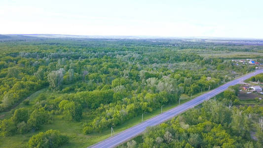 蓝天背景下穿过绿色森林到小镇的鸟瞰图.艺术.