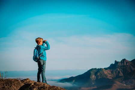 小男孩带着望远镜在山上徒步旅行